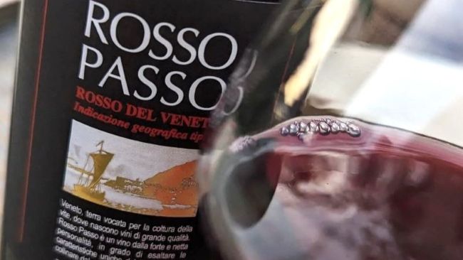 Eine Flasche Rotwein Lenotti Rosso Passo mit einem eingeschenkten Weinglas davor